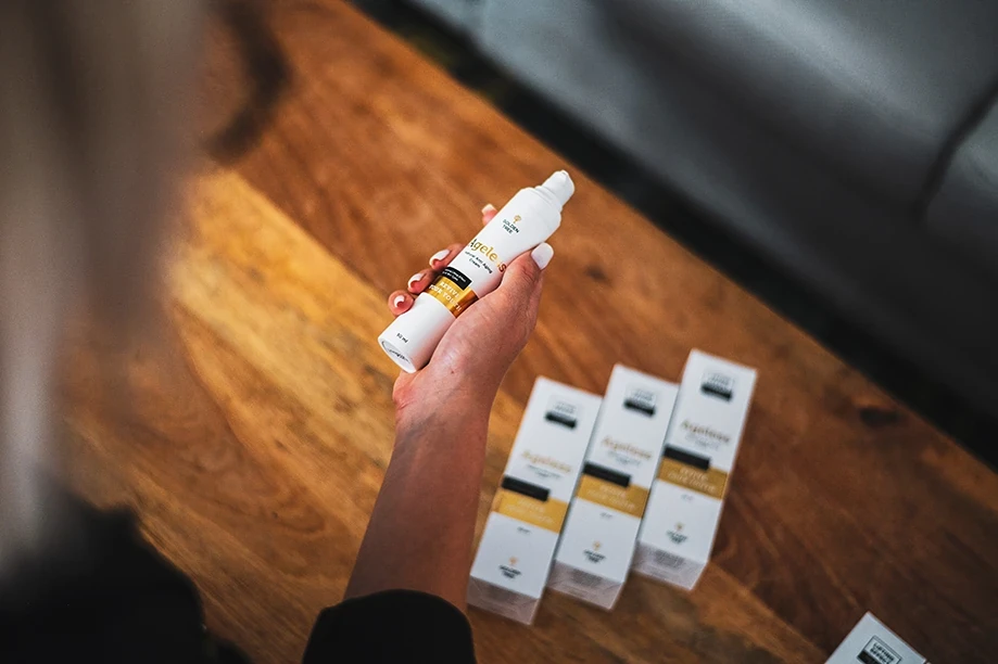 Golden Tree Ageless Creme wird vor mehreren Produktkartons gehalten